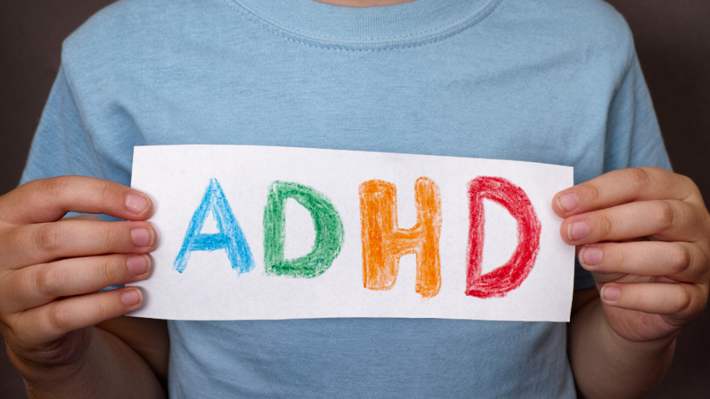 A child holding a paper with ADHD written across it