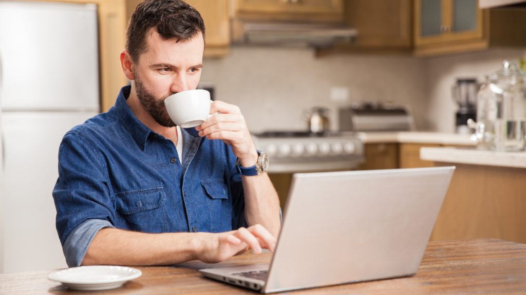 A man sipping on a cup of coffee while working from home